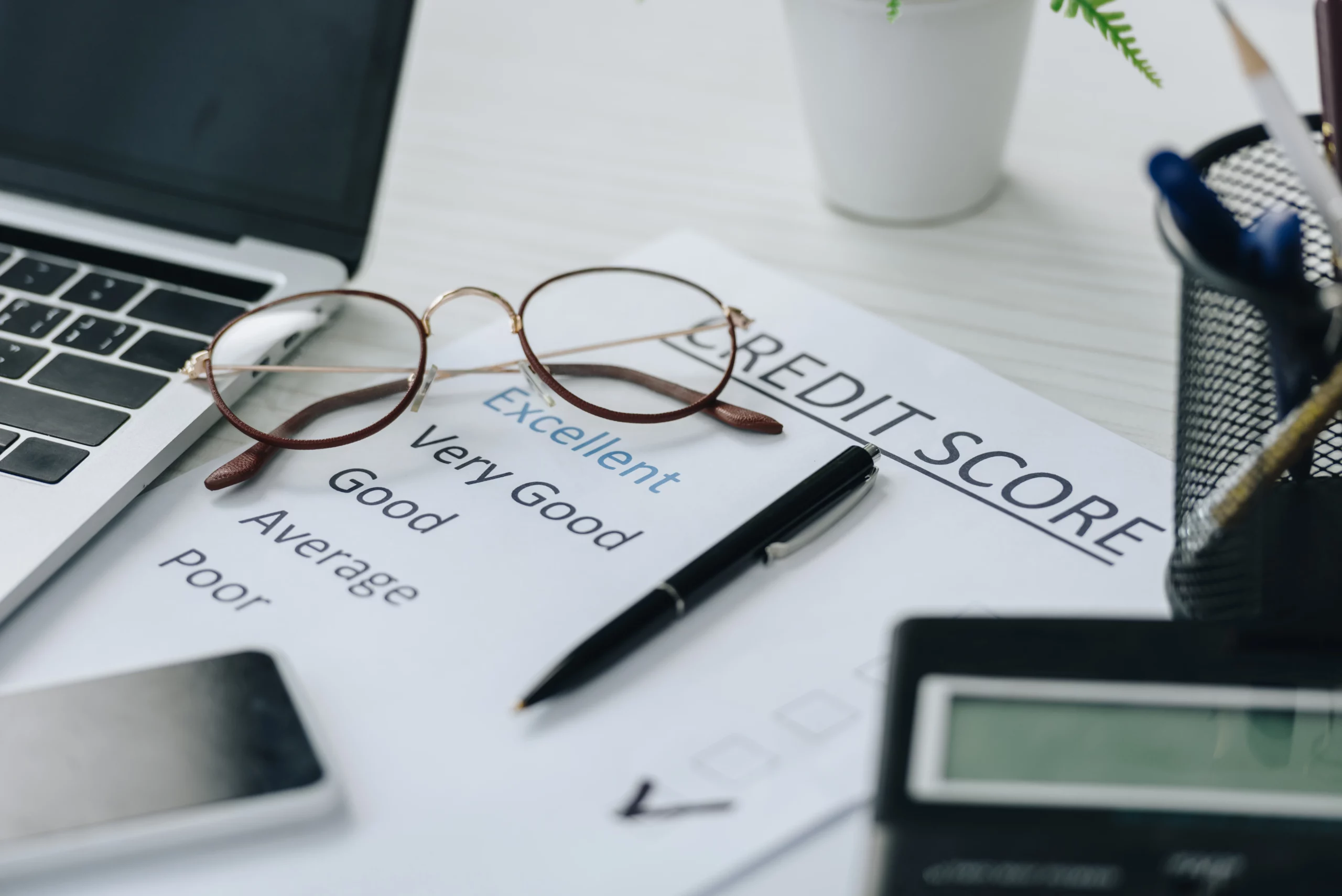Credit report, pen, glasses, and financial tools on desk, symbolizing Chapter 7 bankruptcy's 10-year impact on credit in North Carolina.